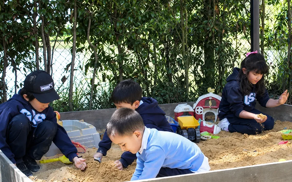 Niños de preescolar jugando y compartiendo juguetes en el arenero de la sede Cajicá