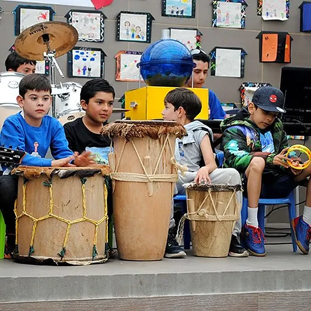 Niños de primaria con tambores de percusión en el salón de música