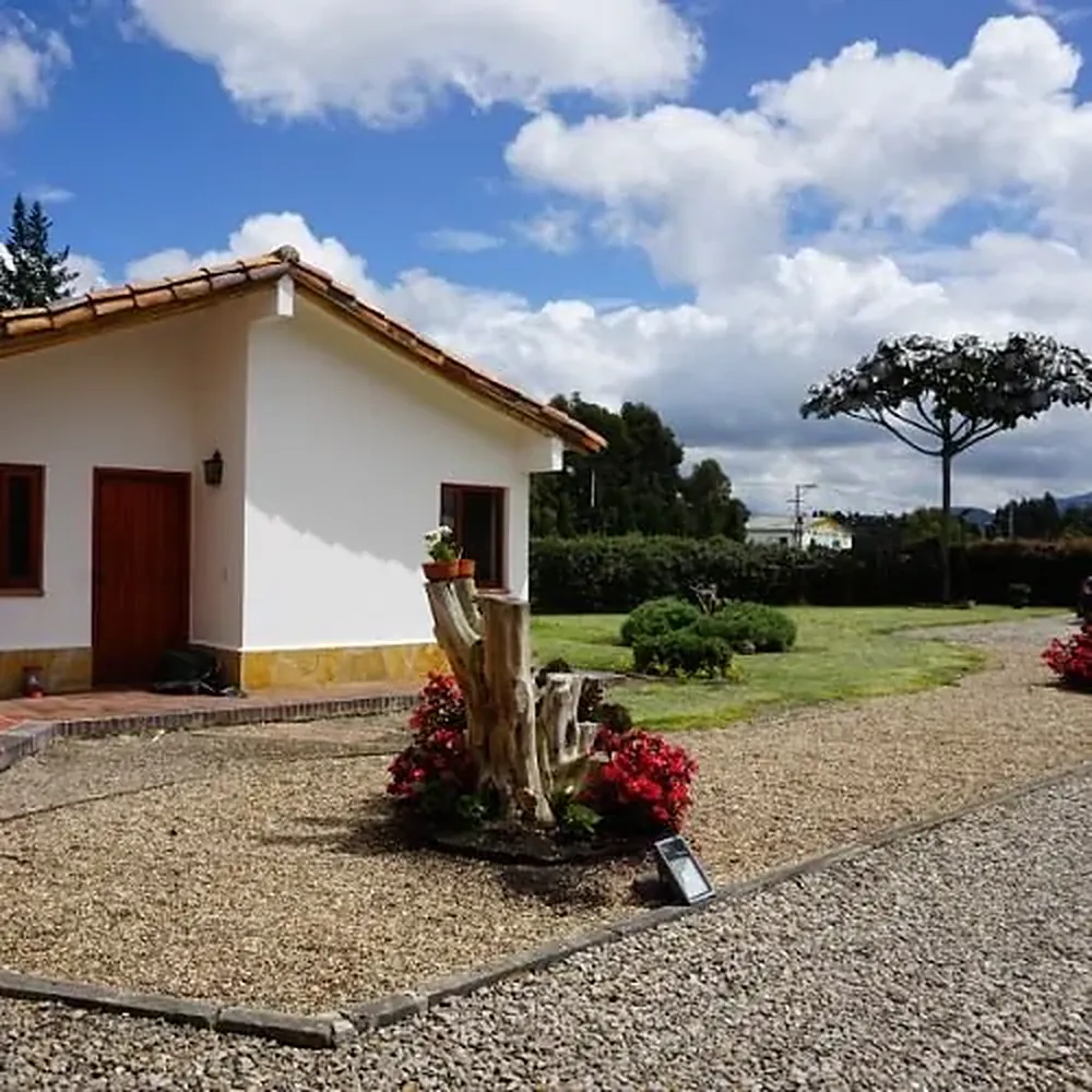 Construcción blanca de teja rodeada de jardín en la sede Chía