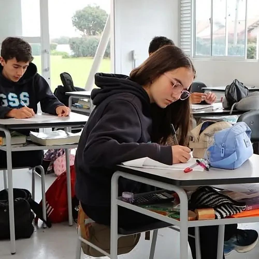 Estudiante de secundaria escribiendo en clase