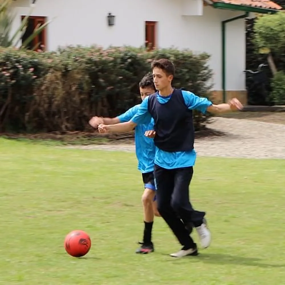 Dos estudiantes jugando fútbol en el prado de la sede Chía