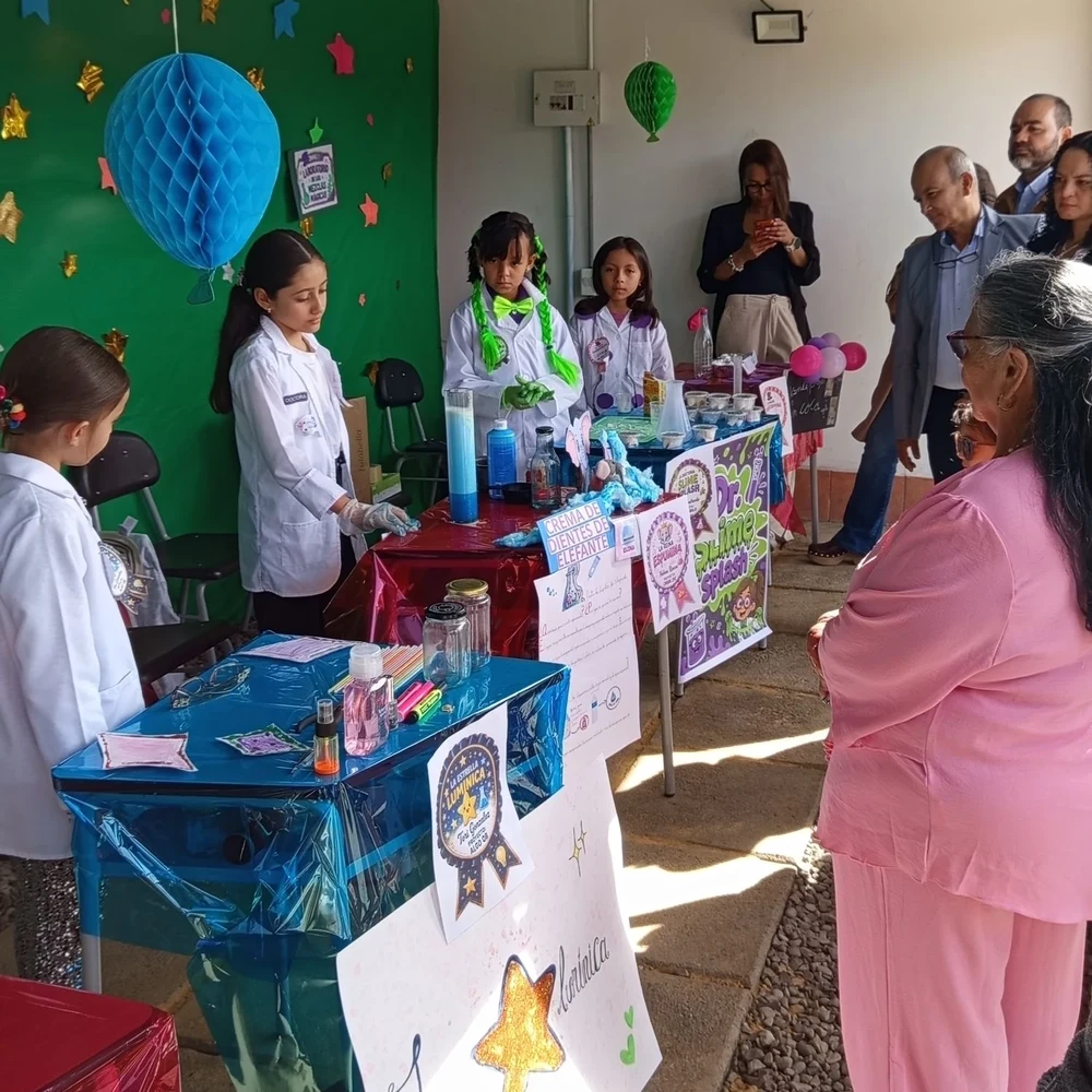 Estudiantes con bata de laboratorio presentando su proyecto en la feria de ciencias