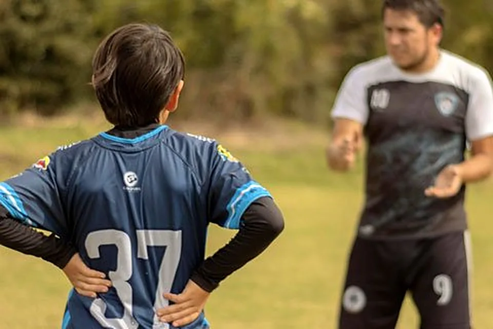 Estudiante con la camiseta 37 escuchando a su entrenador en la cancha