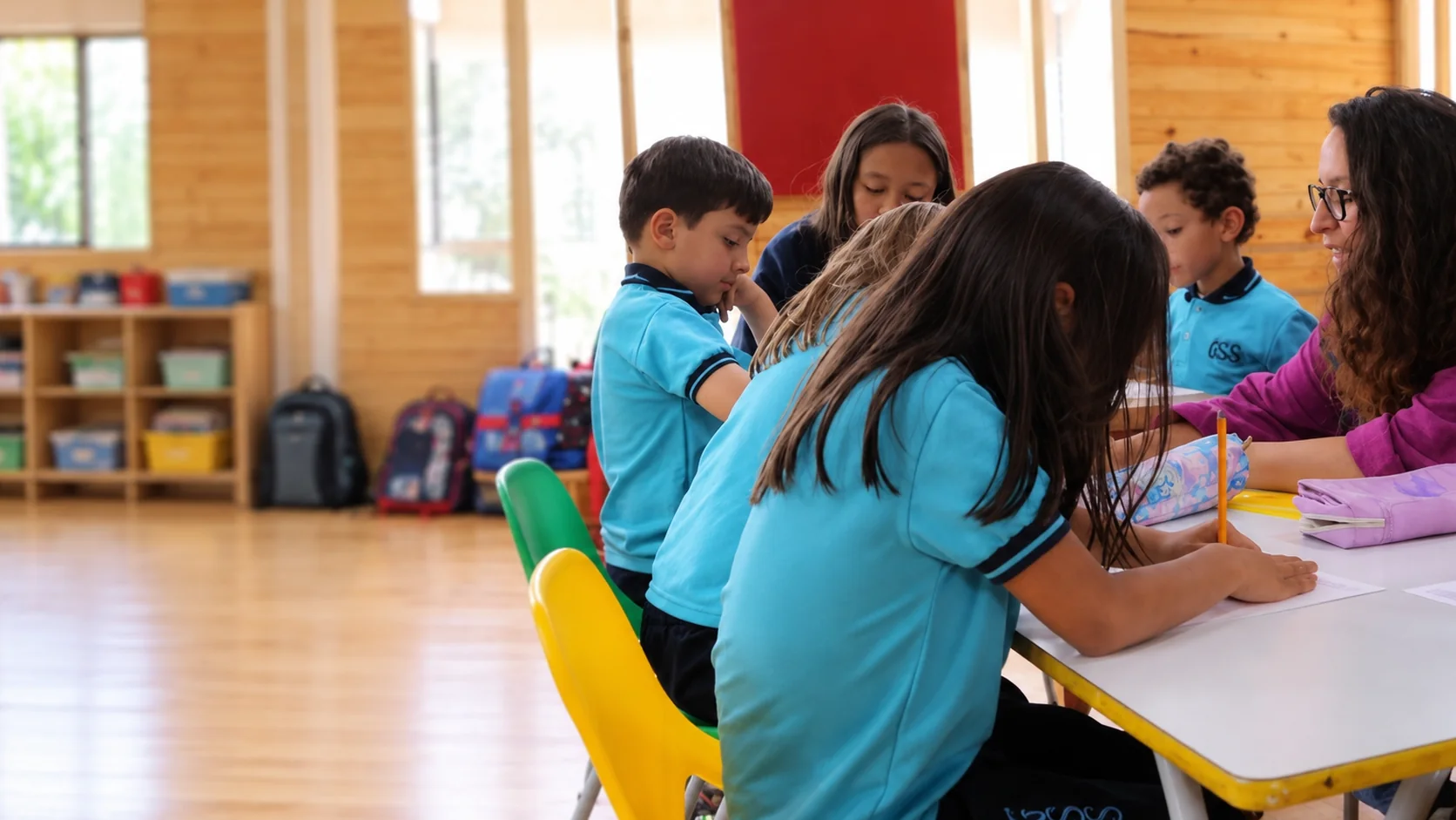 Profesora del Gimnasio Santamaría de la Sabana acompañando a un grupo de niños que trabajan en una mesa