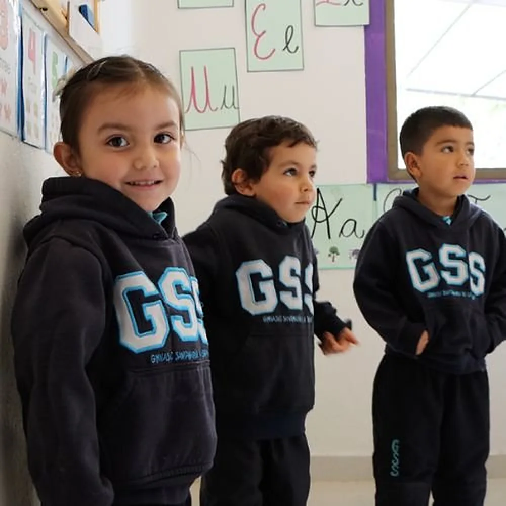 Niños de preescolar con el buzo del colegio en su salón