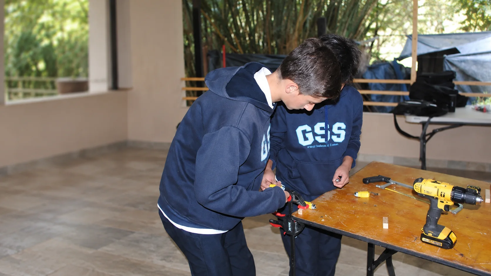 Dos estudiantes del Gimnasio Santamaría de la Sabana trabajando con un taladro en un proyecto