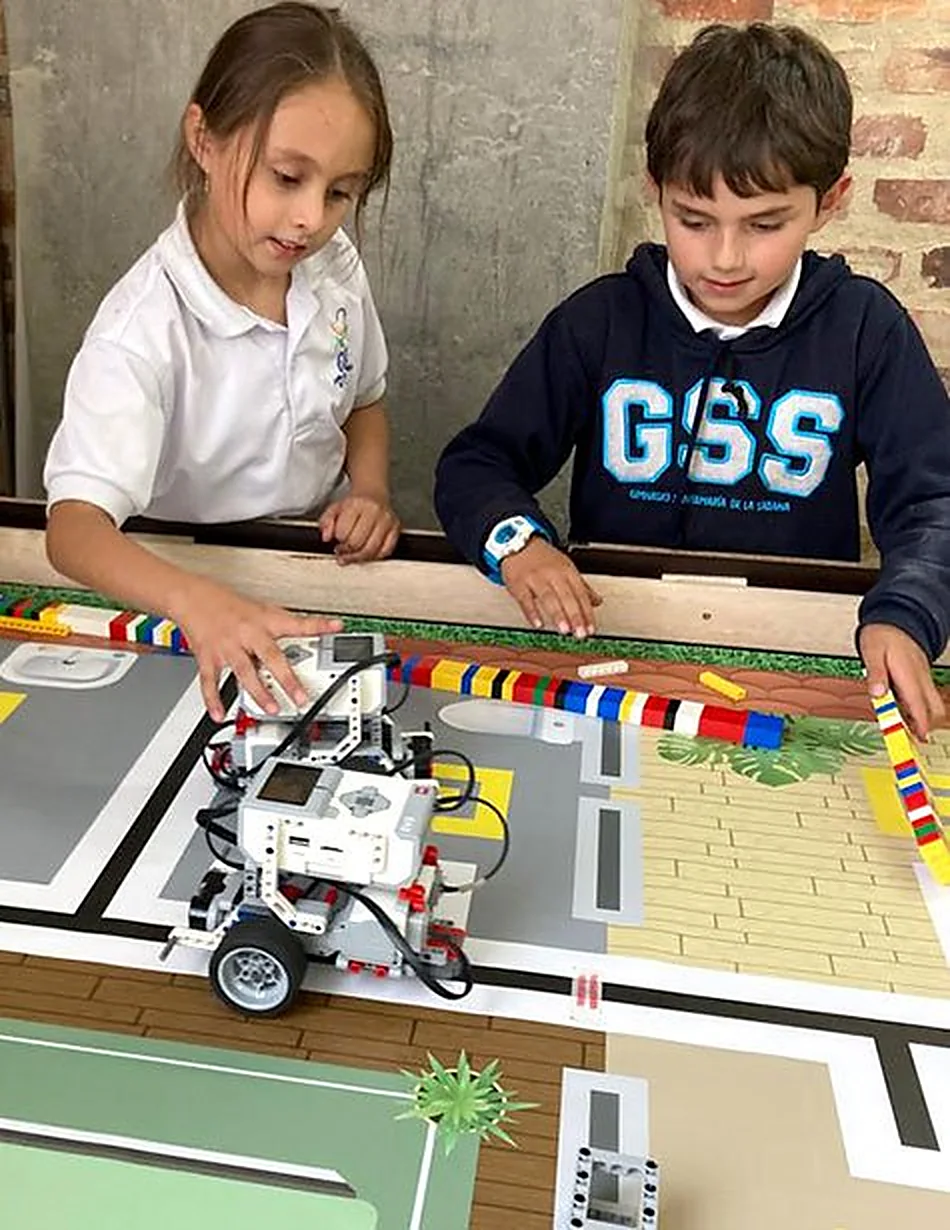 Dos estudiantes programando un robot sobre una pista